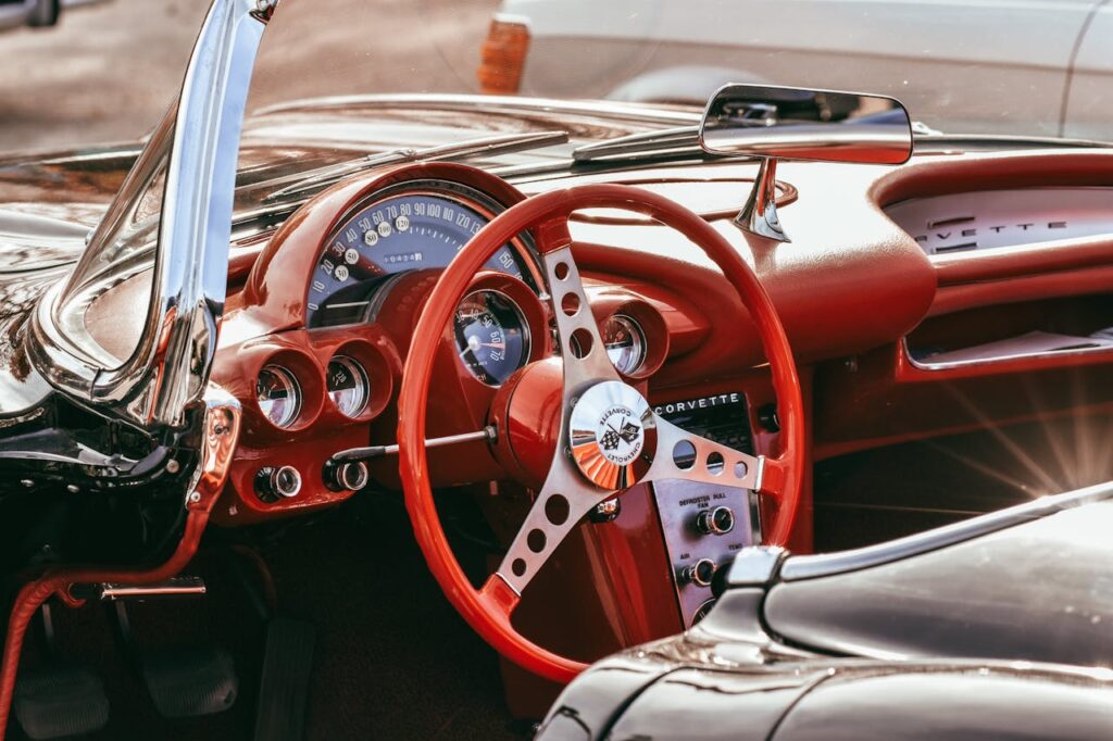 Interior view of a vintage Corvette convertible with red leather and classic dashboard.